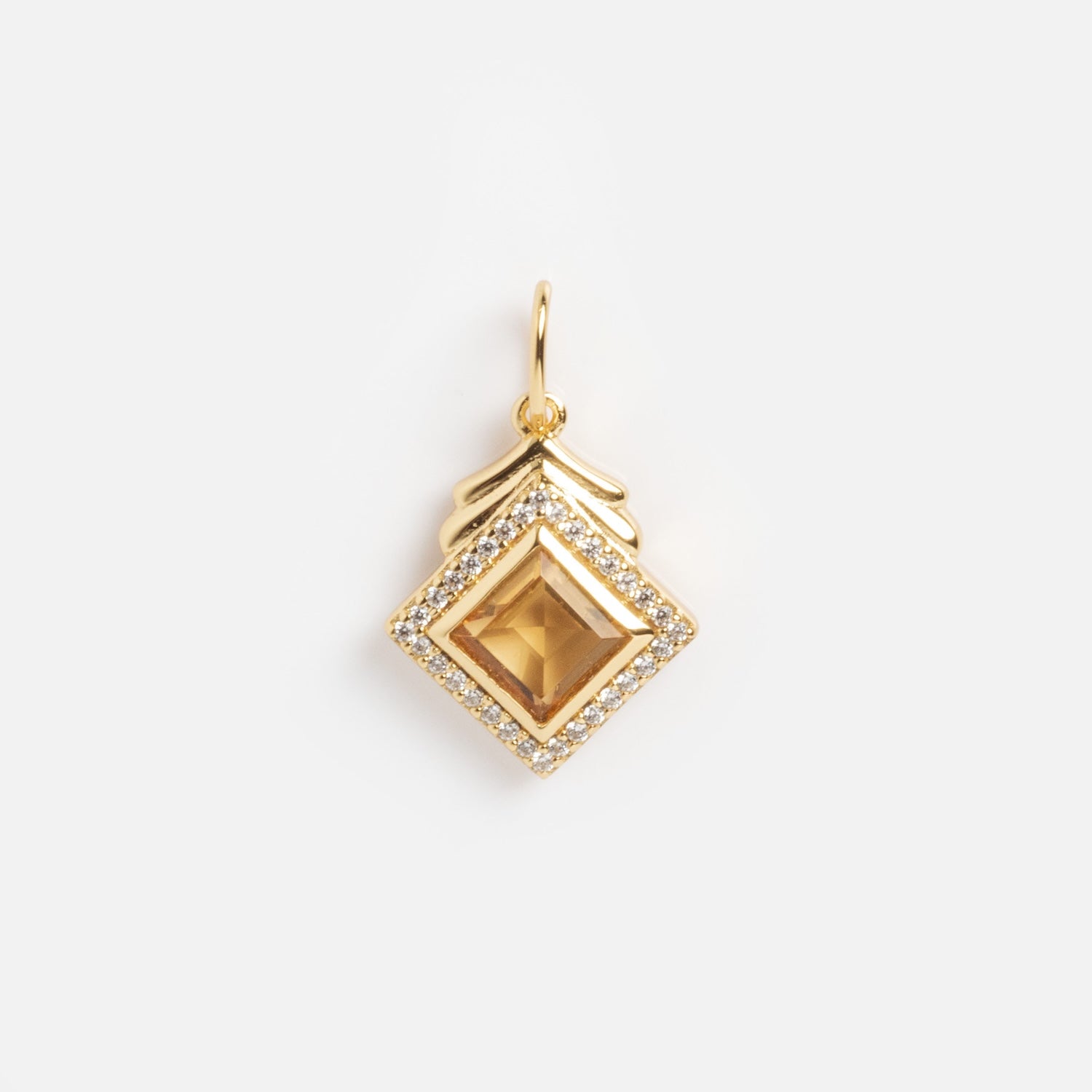 The Vintage Inspired Pendant Charm features a square, pyramid-shaped gemstone at the center, accented by small clear stones and a decorative gold hook, evoking timeless Period Piece style against a plain white background.