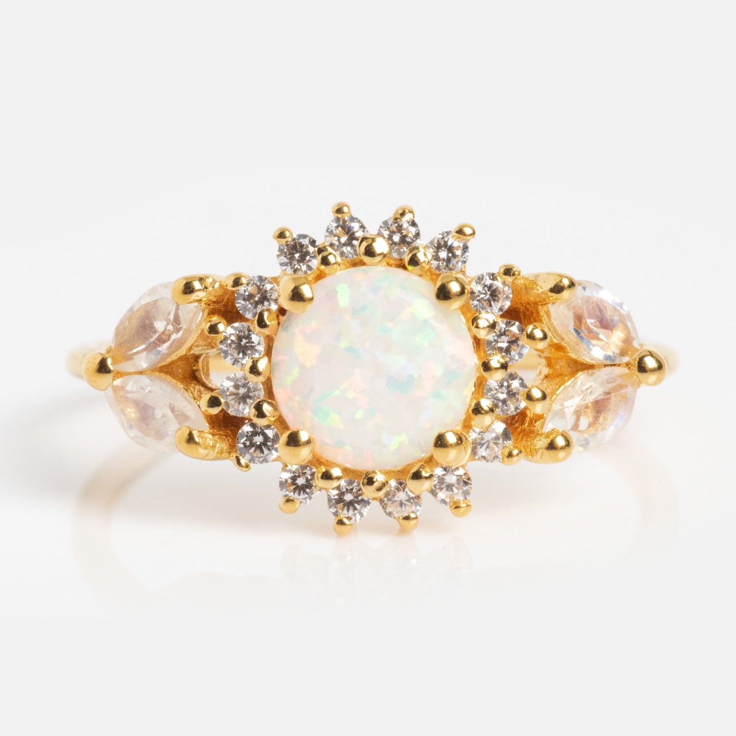 The Opal and Diamond Sunflower Queen Ring showcases a round opal center stone, haloed by clear diamonds with marquise-shaped accents, all set in gold against a white background.