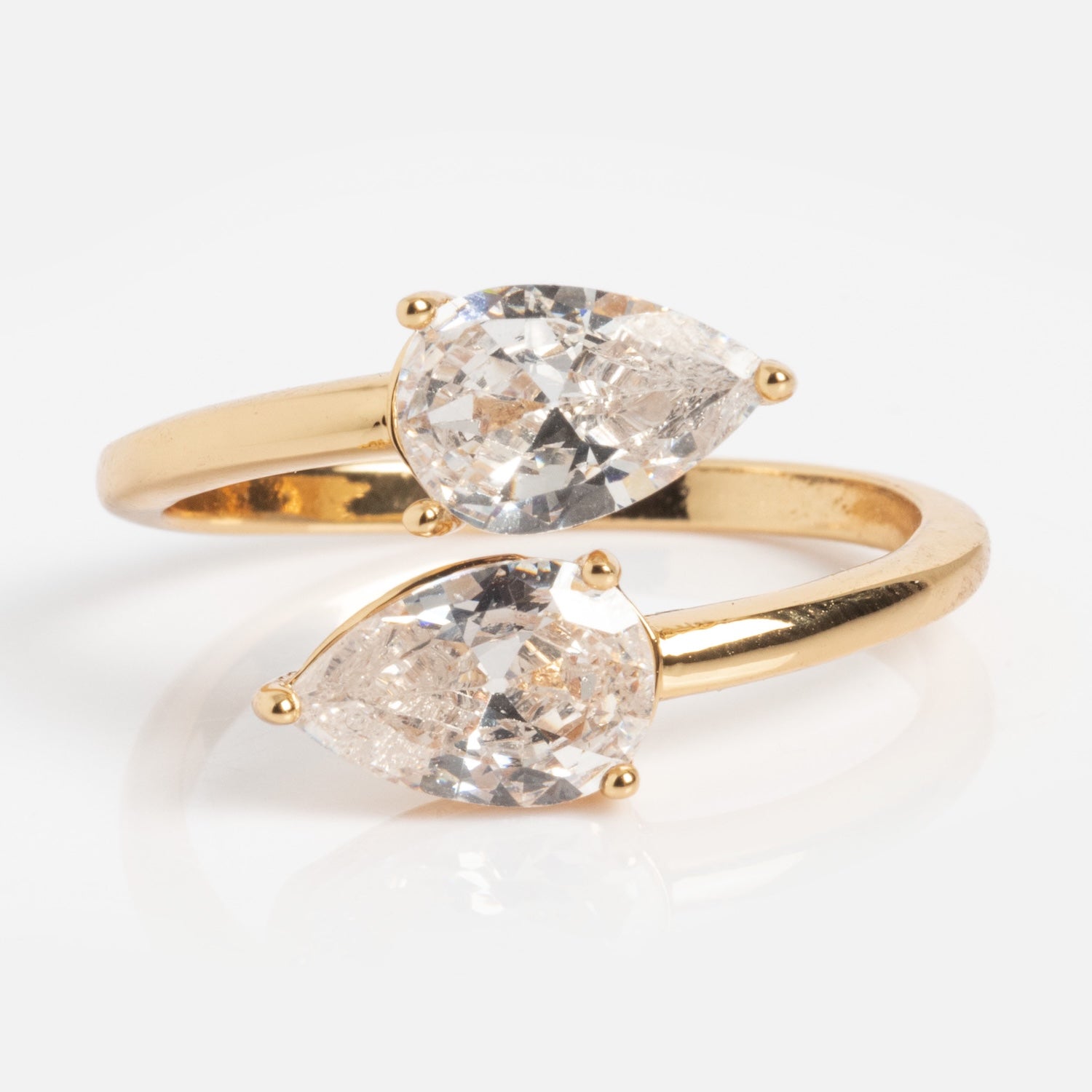 The Crystal Teardrop Wrap Ring features two large, pear-shaped clear gemstones set opposite each other with pointed ends outward, in a modern open-ended gold design against a white background.