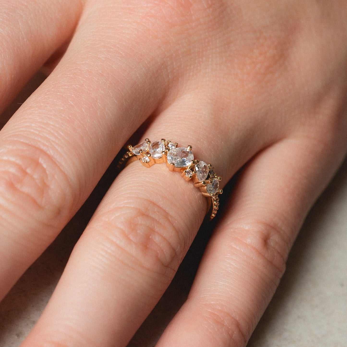 A close-up of a hand wearing the Statement Crystal Cluster Ring, featuring rows of sparkling clear gemstones set in gold.