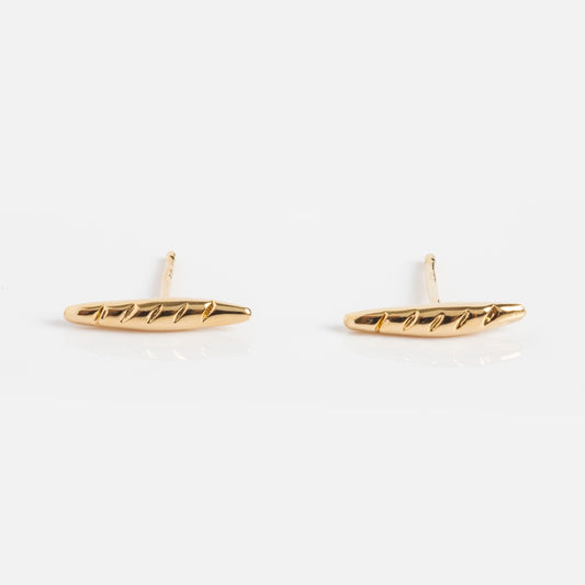 Baguette Studs shaped like miniature baguette loaves with diagonal lines, plated in 12k yellow gold for a Parisian chic look, shown on a plain white background.