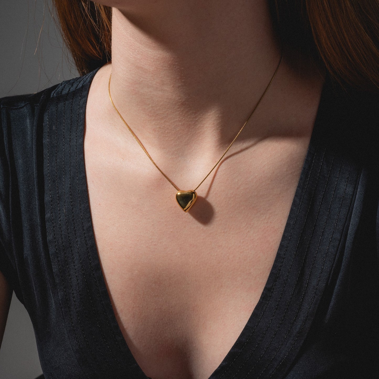 A woman wears a deep navy V-neck top and a delicate yellow necklace.
