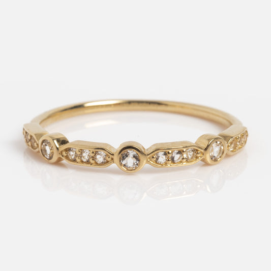 The Solid Gold Bezeled Shimmer Stacking Ring features small round diamonds set in a repeating bezel and pavé pattern along the band, shown against a white background.