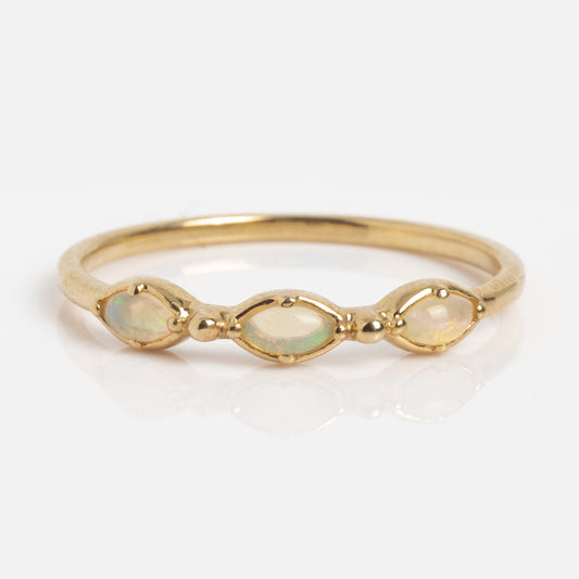 The Solid Gold Dainty Opal Trio Stacking Ring showcases three oval opals in a row, accented with small gold beads, and is displayed on a white background.