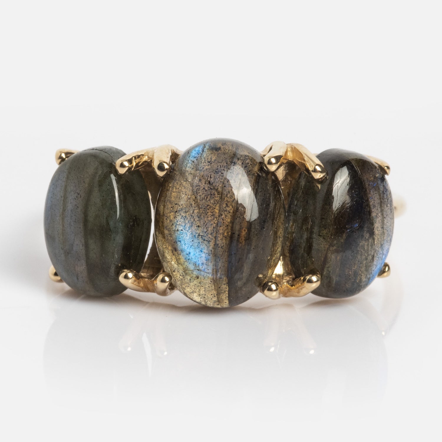 The Sweetest Gumdrop Ring features four oval, polished labradorite gemstones with blue and gold flashes, set in solid yellow gold prongs, arranged in a row against a white background.