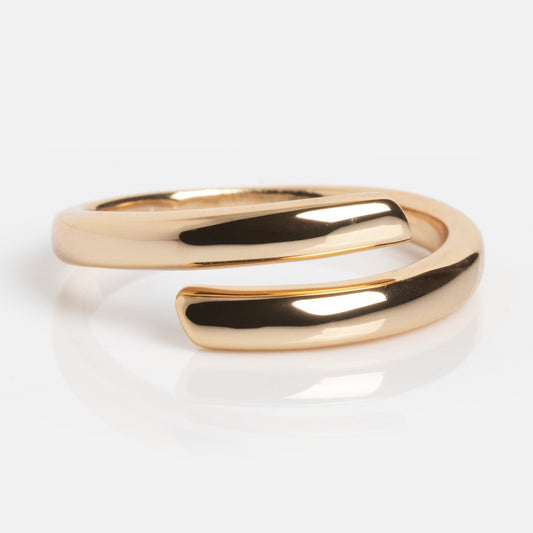 The Wrap Around Ring features a shiny, polished gold finish with an open-ended, minimalist design and smoothly curved edges, displayed on a white surface.
