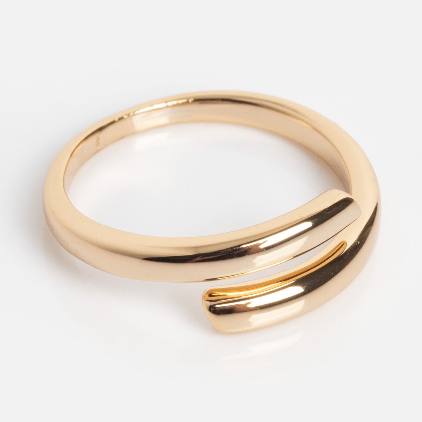 Introducing the Wrap Around Ring: a modern gold ring with an open-ended design, featuring two smooth, slightly overlapping ends displayed on a plain white background.