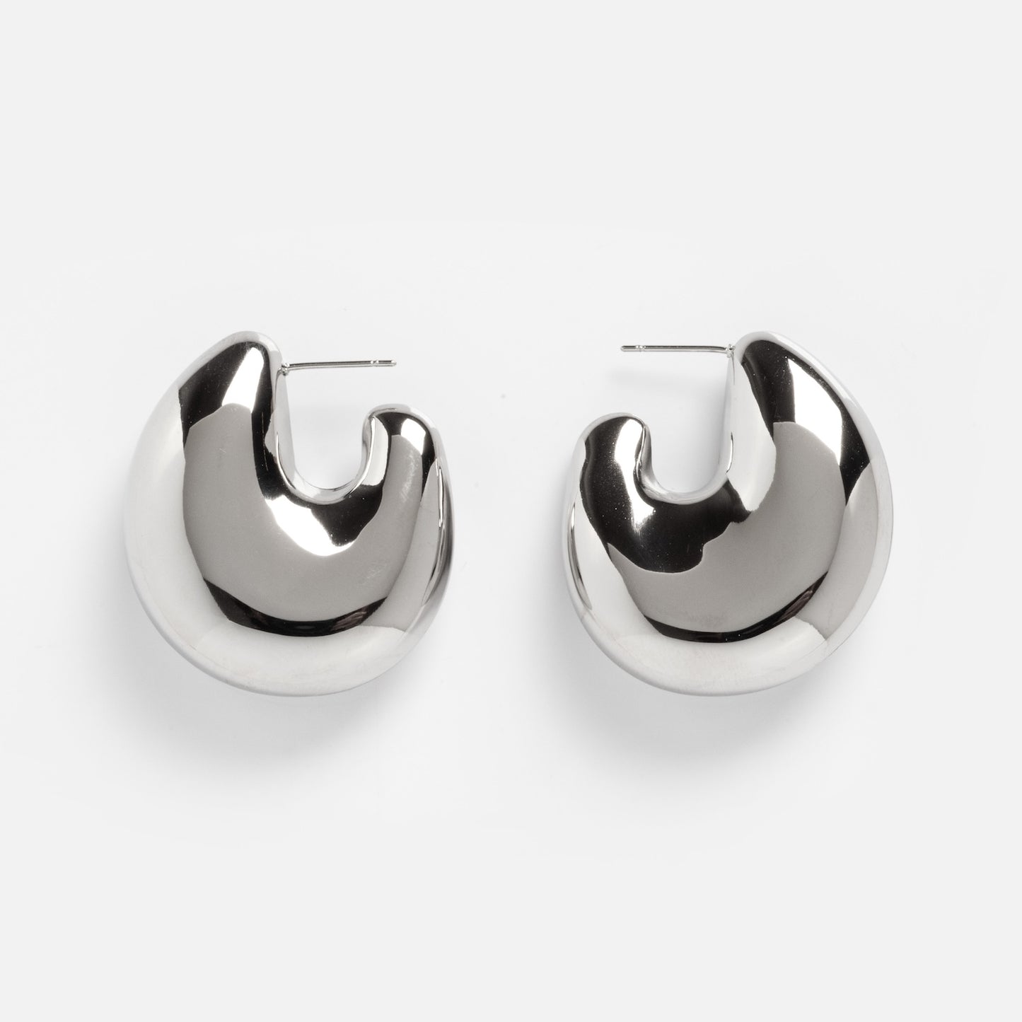 The Remy Earrings are shiny, silver chunky hoops with a smooth, rounded crescent shape, shown on a plain white background.