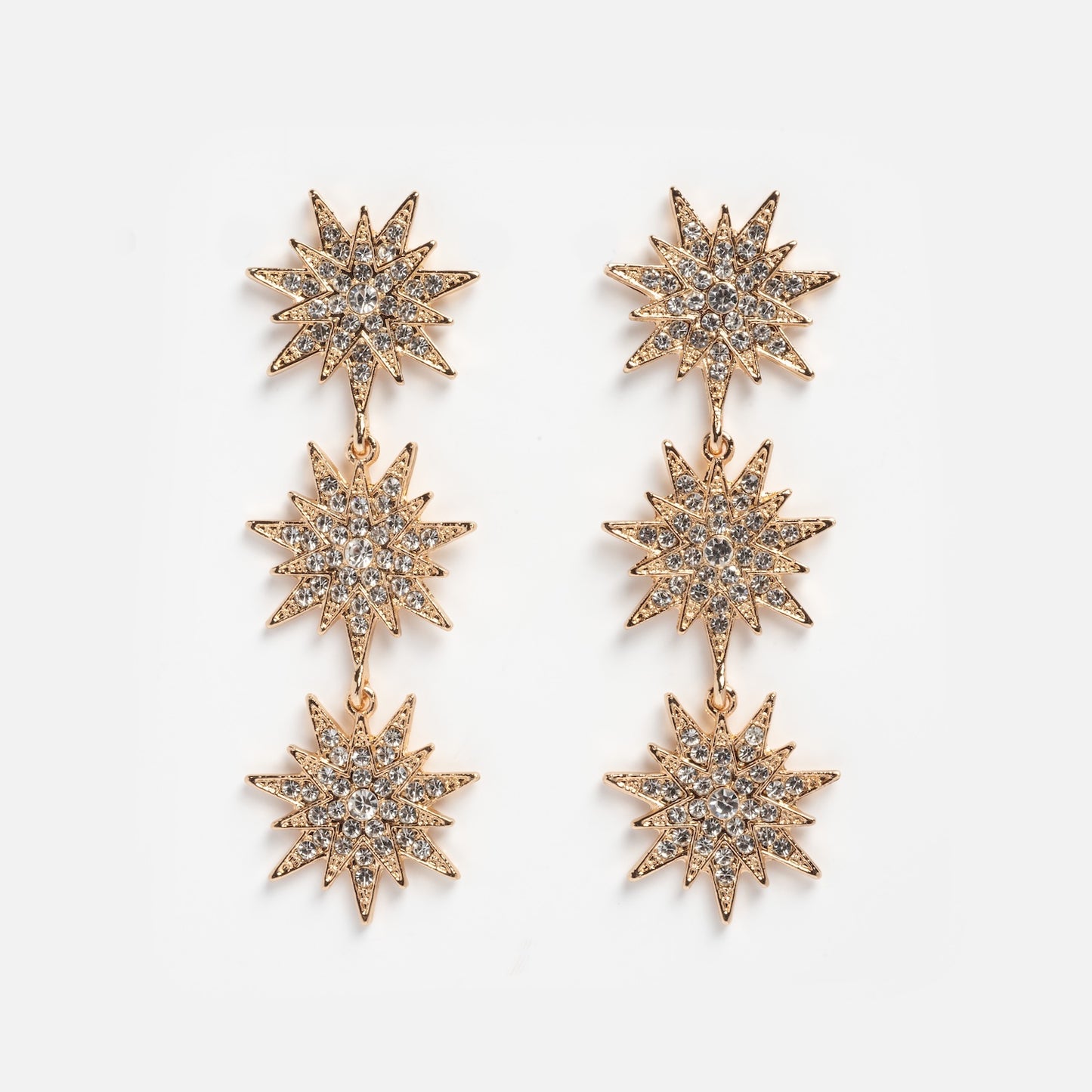 Celestial Drop Earrings in gold-tone, with three sparkling starburst shapes encrusted with clear rhinestones arranged vertically, shown on a plain white background.