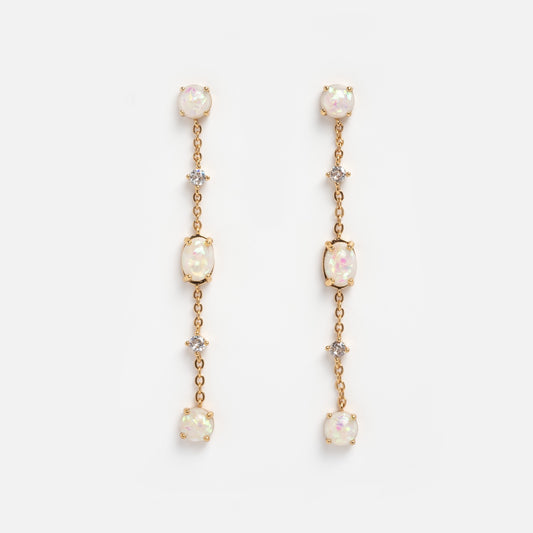 The Elegant Opal Sway Dangle Earrings feature three round opal-like stones and two small clear crystals arranged vertically on a delicate gold chain, displayed against a plain white background.