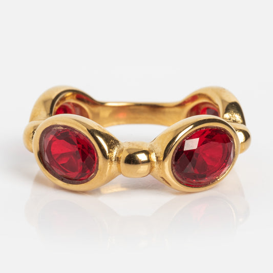 The Bita Ring is a gold band adorned with large, oval-shaped red gemstones set in rounded bezels, arranged in a continuous pattern around the ring.