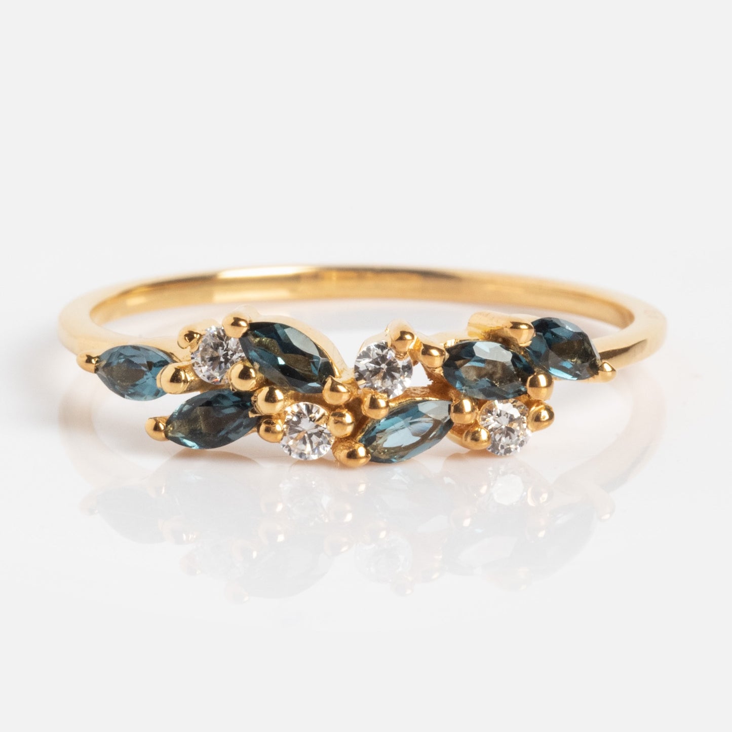 The Gemstone Orchard Ring is a gold ring with marquise-shaped London blue topaz and round white diamonds arranged organically on a slender band.