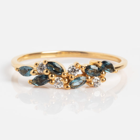 The Gemstone Orchard Ring is a gold ring with marquise-shaped London blue topaz and round white diamonds arranged organically on a slender band.