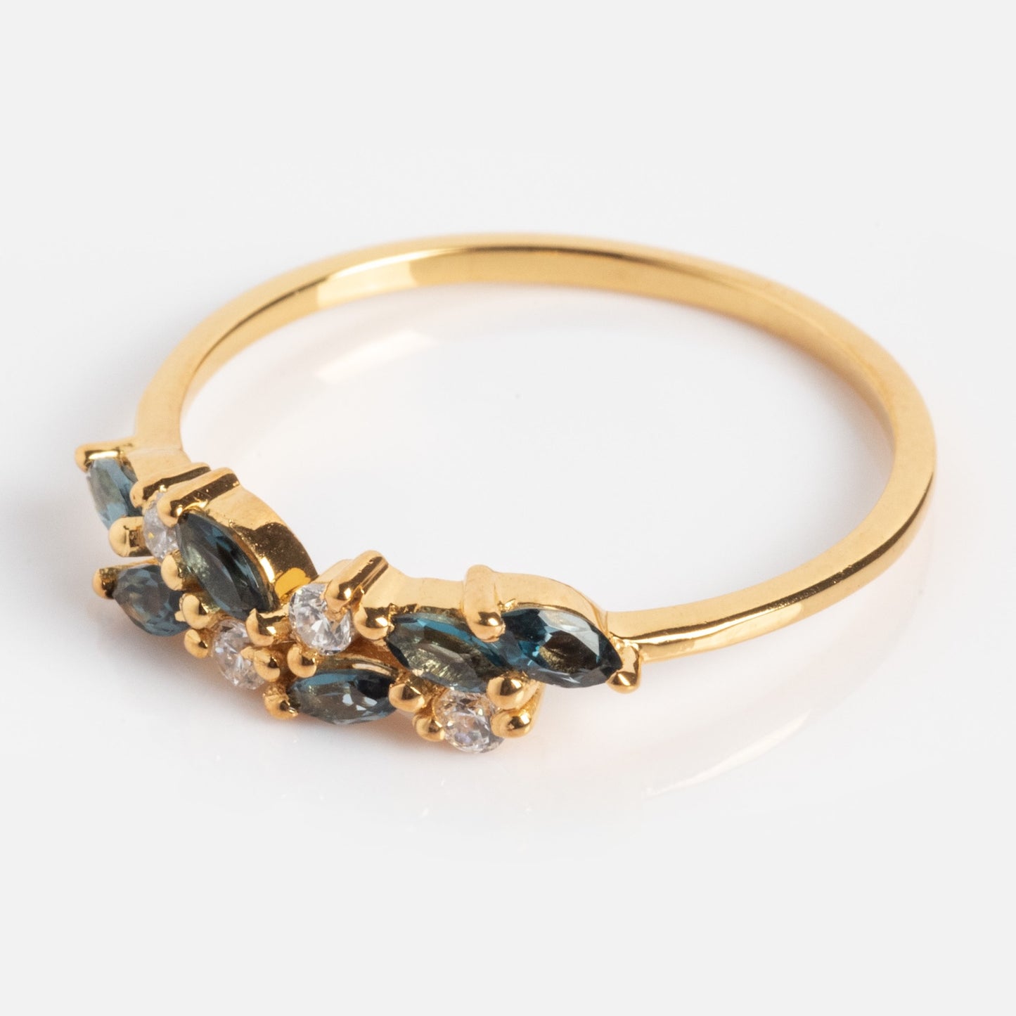 The Gemstone Orchard Ring features alternating marquise London blue topaz and round clear stones in a row on a polished gold band, beautifully displayed on a white background.