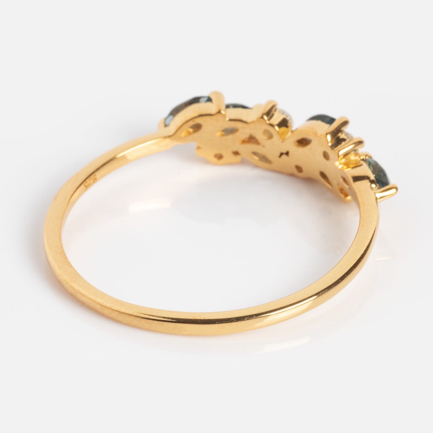 The Gemstone Orchard Ring is a gold ring with a thin band and a decorative setting holding three London blue topaz stones, shown against a plain white background.