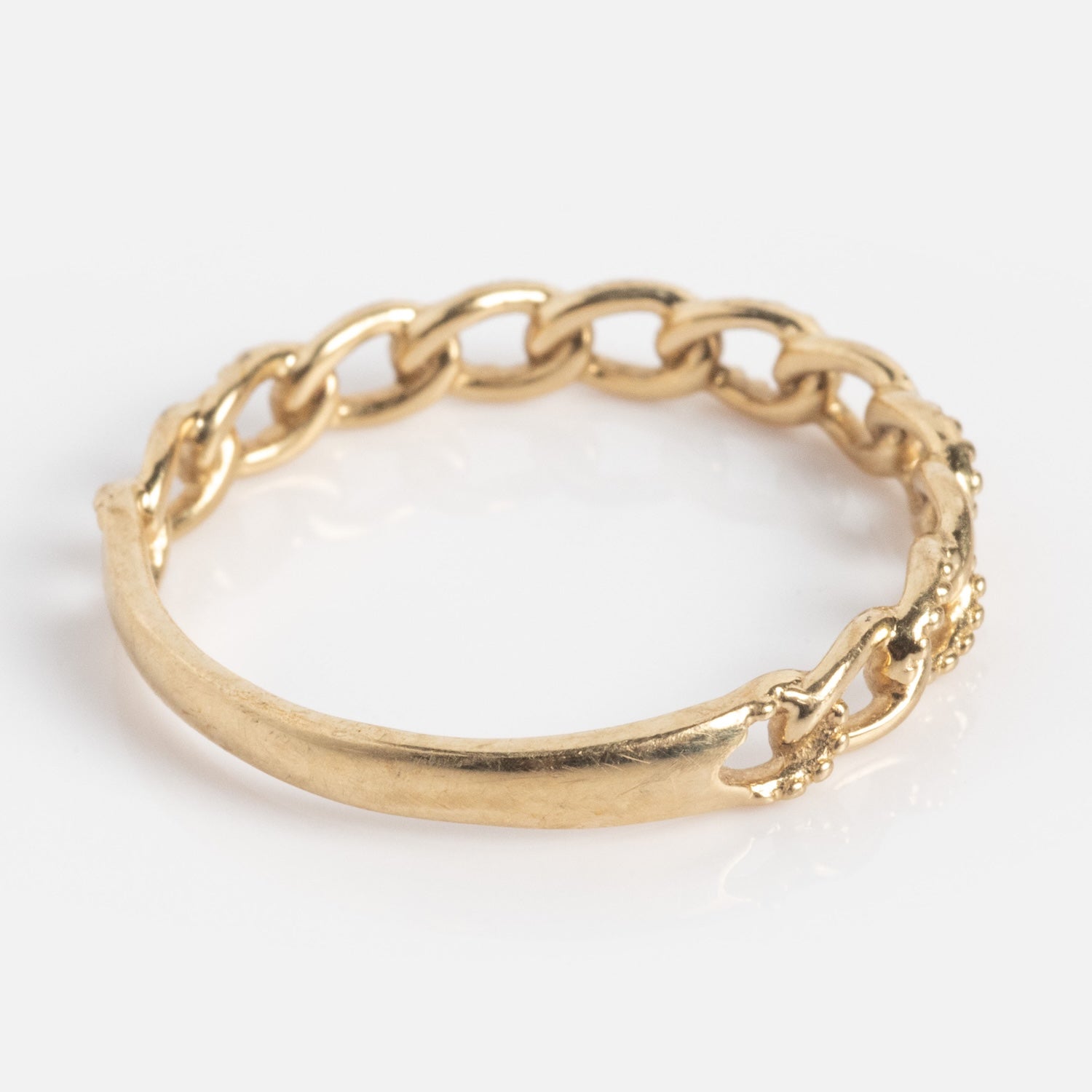 The Solid Gold Textured Chain Link Ring features a smooth 9k gold band on one side and a chain-link design on the other, shown against a white background.