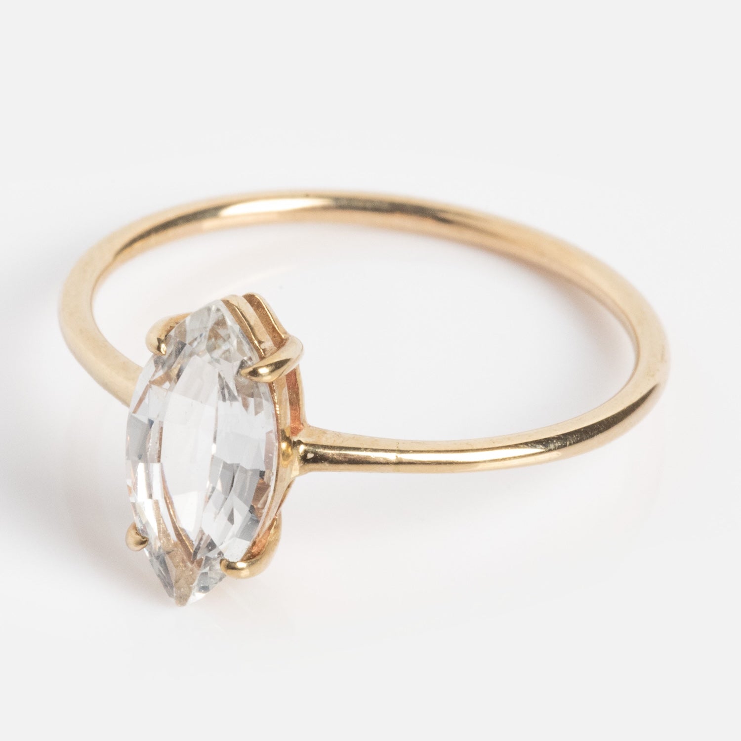 The Solid Gold Gemstone Marquise Ring in White Topaz features a clear marquise-cut topaz in a simple gold prong setting, shown on a white background.