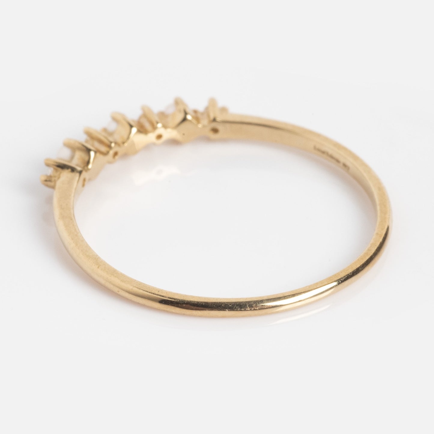 The Solid Gold Pearl Trio Ring features a thin yellow gold band adorned with three delicate pearls along the top, displayed on a plain white background.