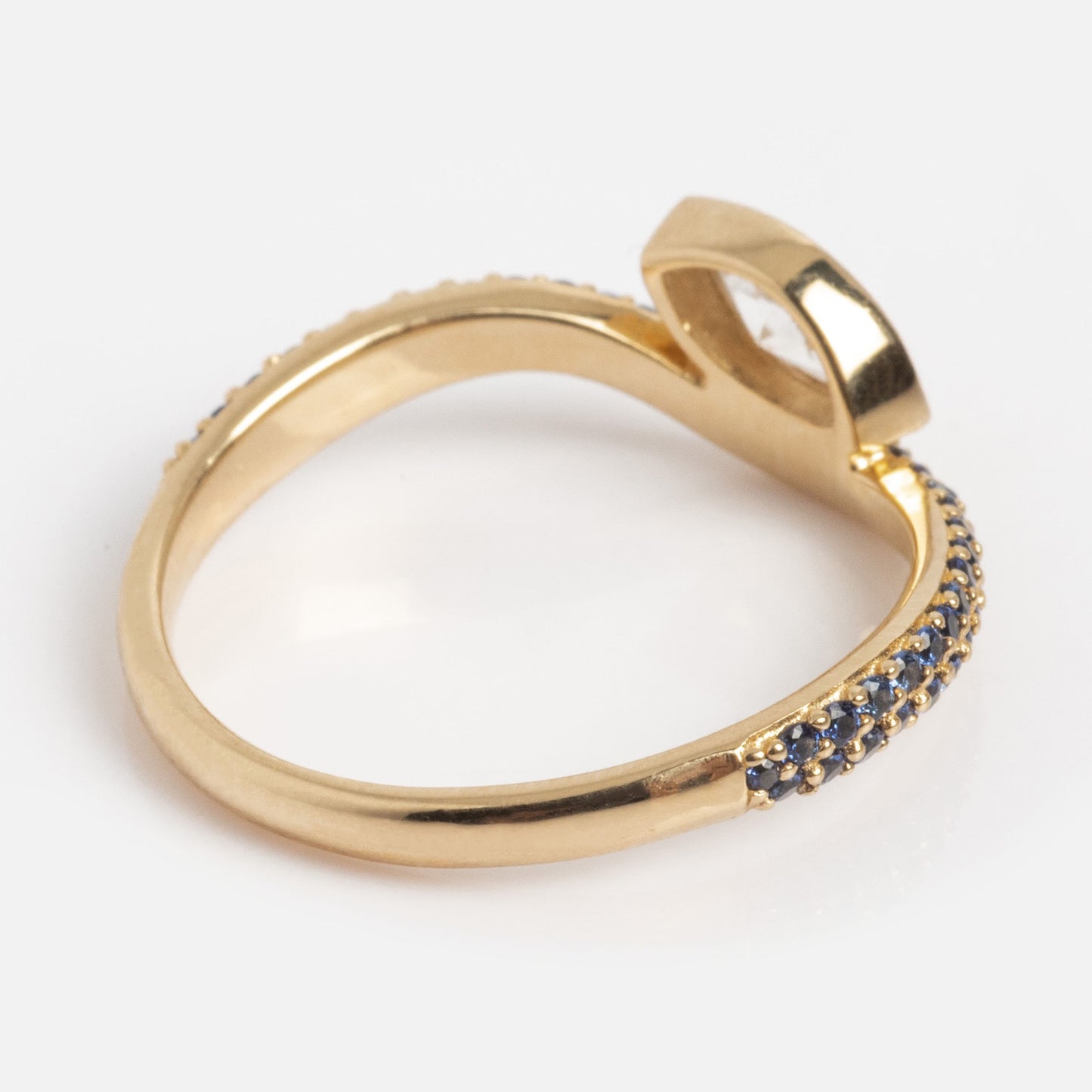 The Solid Gold Nesting Gleam Sapphire and Diamond Ring features a twisted band, accented with small blue sapphires on one side and a prominent elevated diamond, shown against a white background.