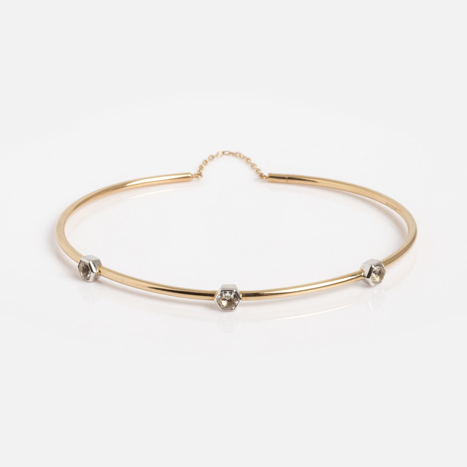 The Solid Gold Geometric Glimmer Mixed Metal Bracelet showcases three small silver hexagonal accents, each with a clear stone, against a plain white background.