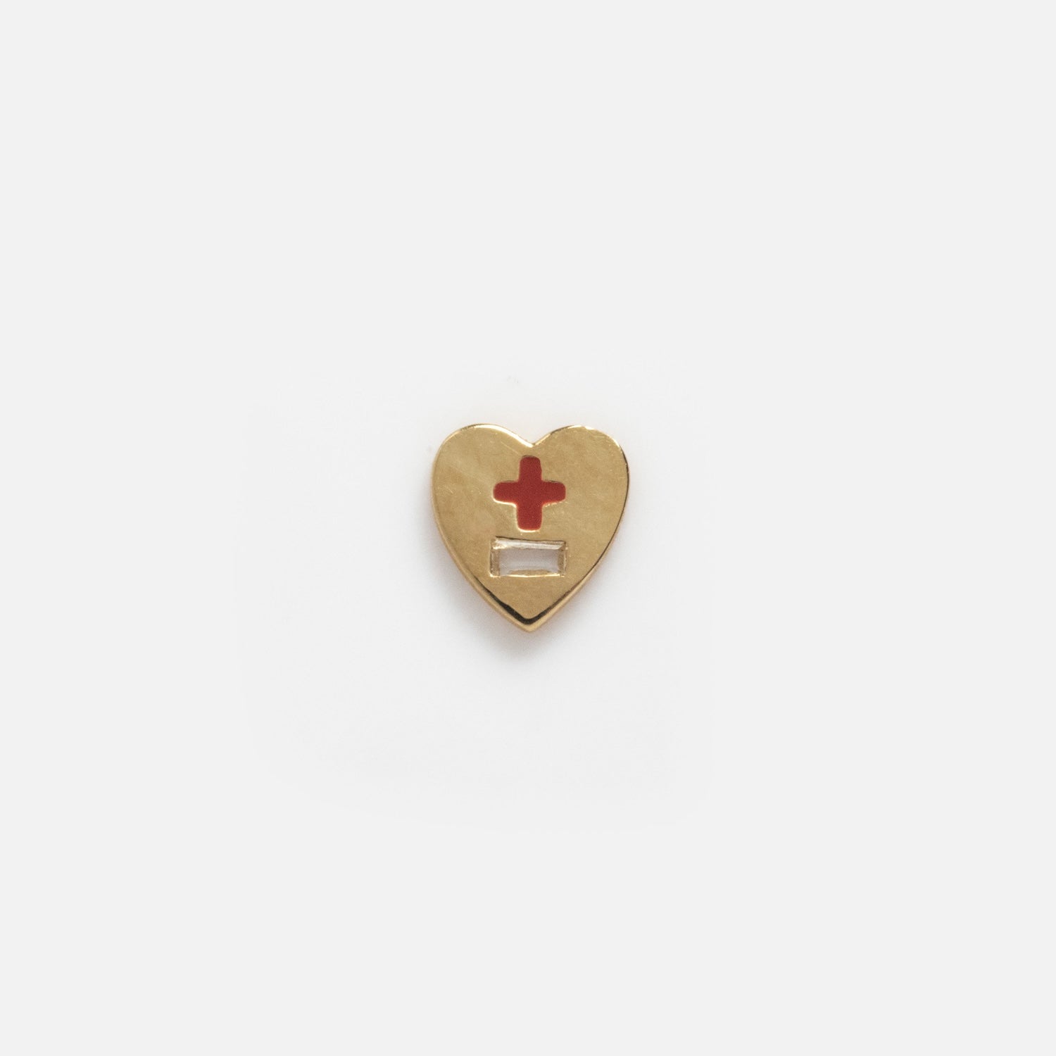 The Solid Gold Tiny Lucky Charm for Glass Charm Locket is a gold heart-shaped pin inspired by yellow gold charms, featuring a red cross above a blank white rectangle on a plain white background.