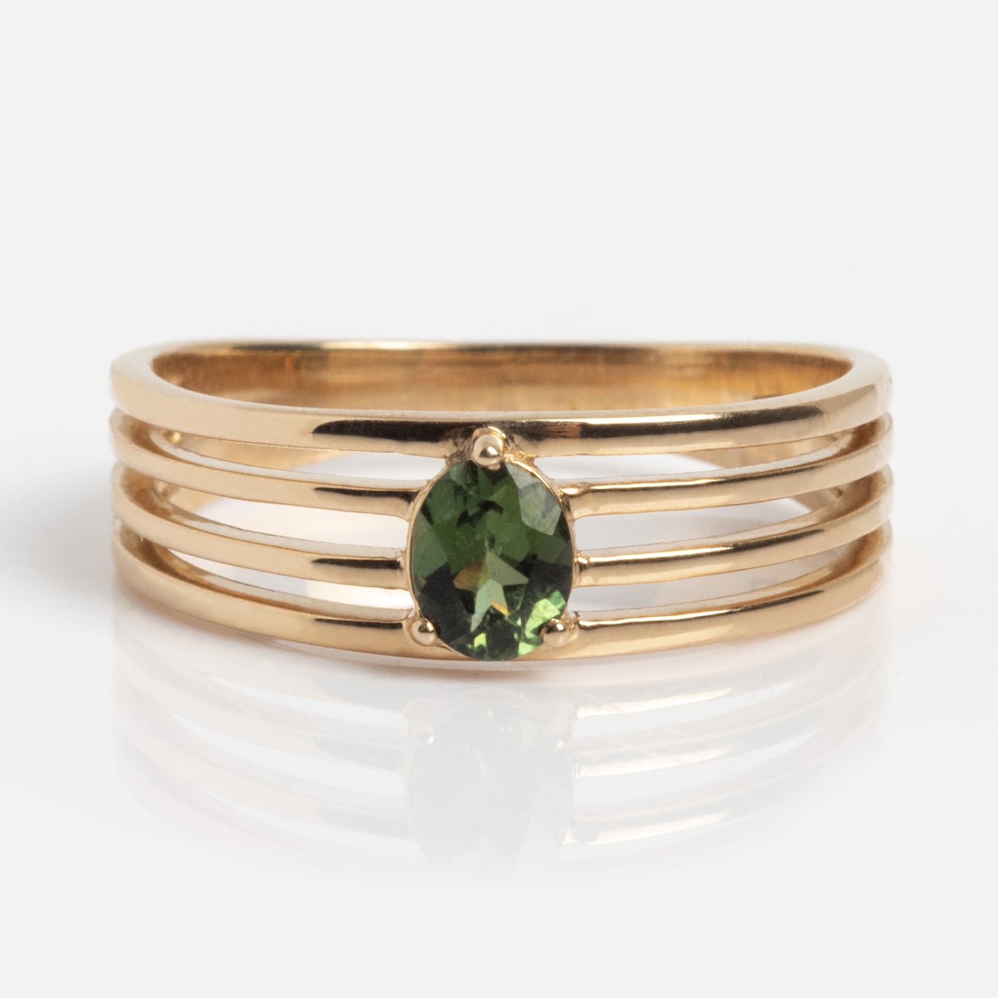 The Solid Gold Stacked Horizon Tourmaline Ring features three parallel gold bands and an oval green tourmaline centerpiece, displayed on a plain white background.