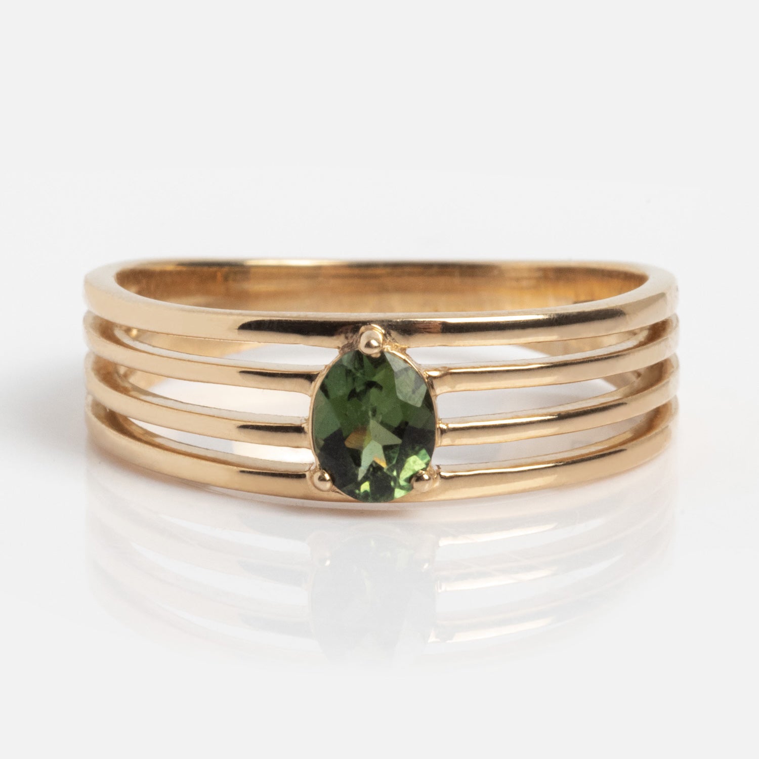 The Solid Gold Stacked Horizon Tourmaline Ring features three parallel gold bands and an oval green tourmaline centerpiece, displayed on a plain white background.