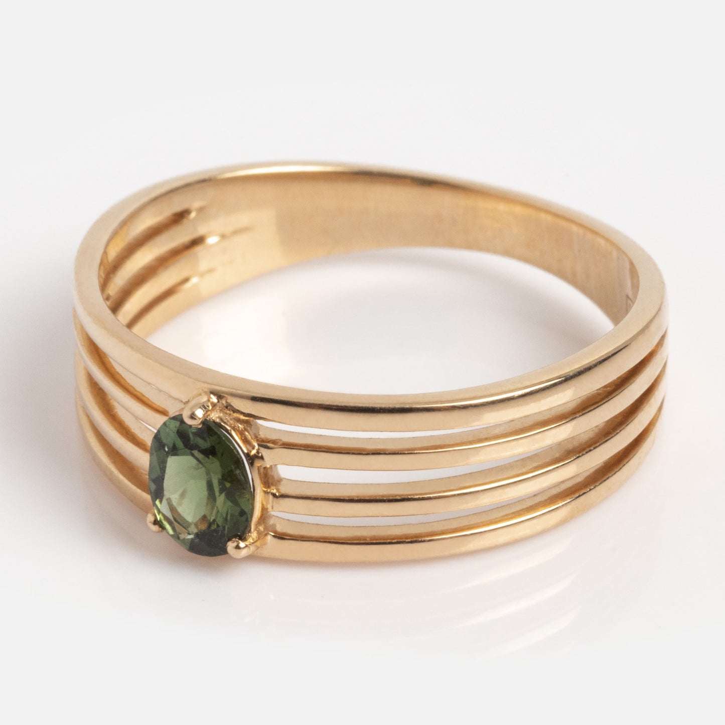 The Solid Gold Stacked Horizon Tourmaline Ring features four parallel gold bands and an oval green tourmaline gemstone set at the center, showcased against a plain white background.