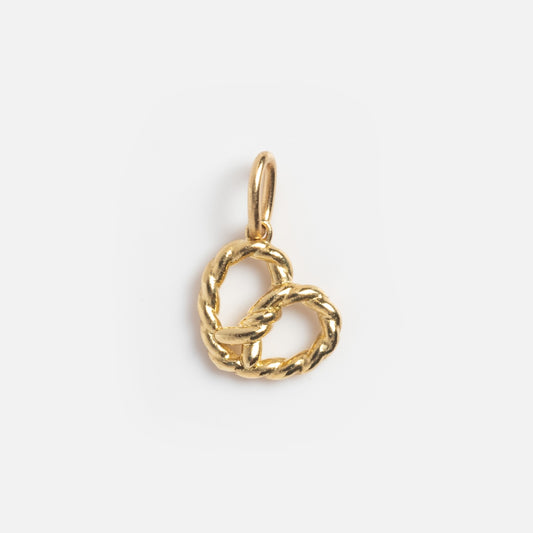 The Solid Gold Foodie Charm is a small 9k yellow gold pretzel-shaped charm with a top loop for attaching to a necklace or bracelet, shown on a plain white background.