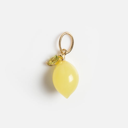 The Solid Gold Foodie Charm is a small, yellow, lemon-shaped necklace with a gold ring and green leaf detail, shown isolated on a white background.