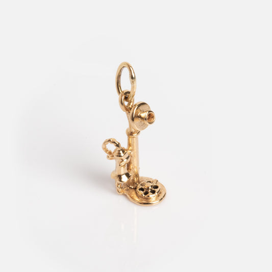 The Vintage 14k Rotary Telephone Charm is a small gold charm shaped like an old-fashioned telephone with a circular base, upright receiver, and top loop for attaching to a chain or bracelet.