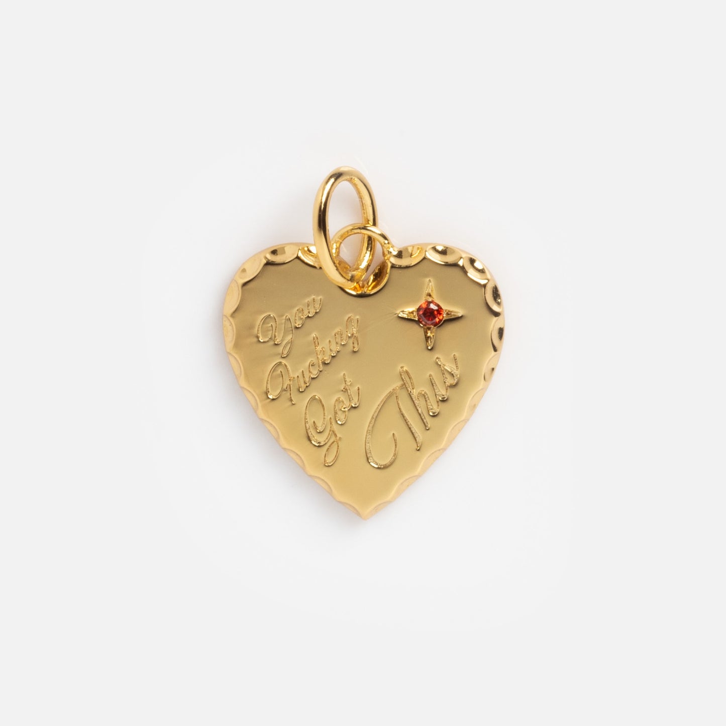 The Curse Word Charm is a gold heart-shaped pendant engraved with "You Fucking Got This," featuring a small red gem at the top right and two loops for attaching to a chain.