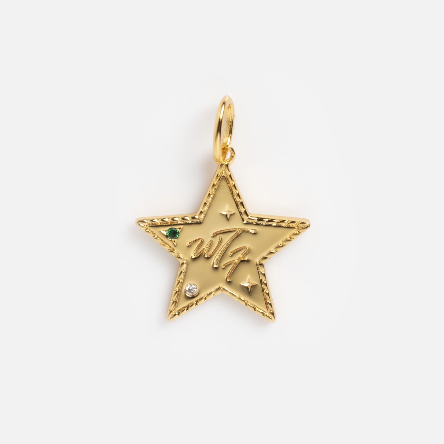 The Curse Word Charm is a gold star-shaped pendant featuring a textured edge, small green and clear gemstones, engraved stars, and the w7 initials in cursive on the front, attached to a gold loop.