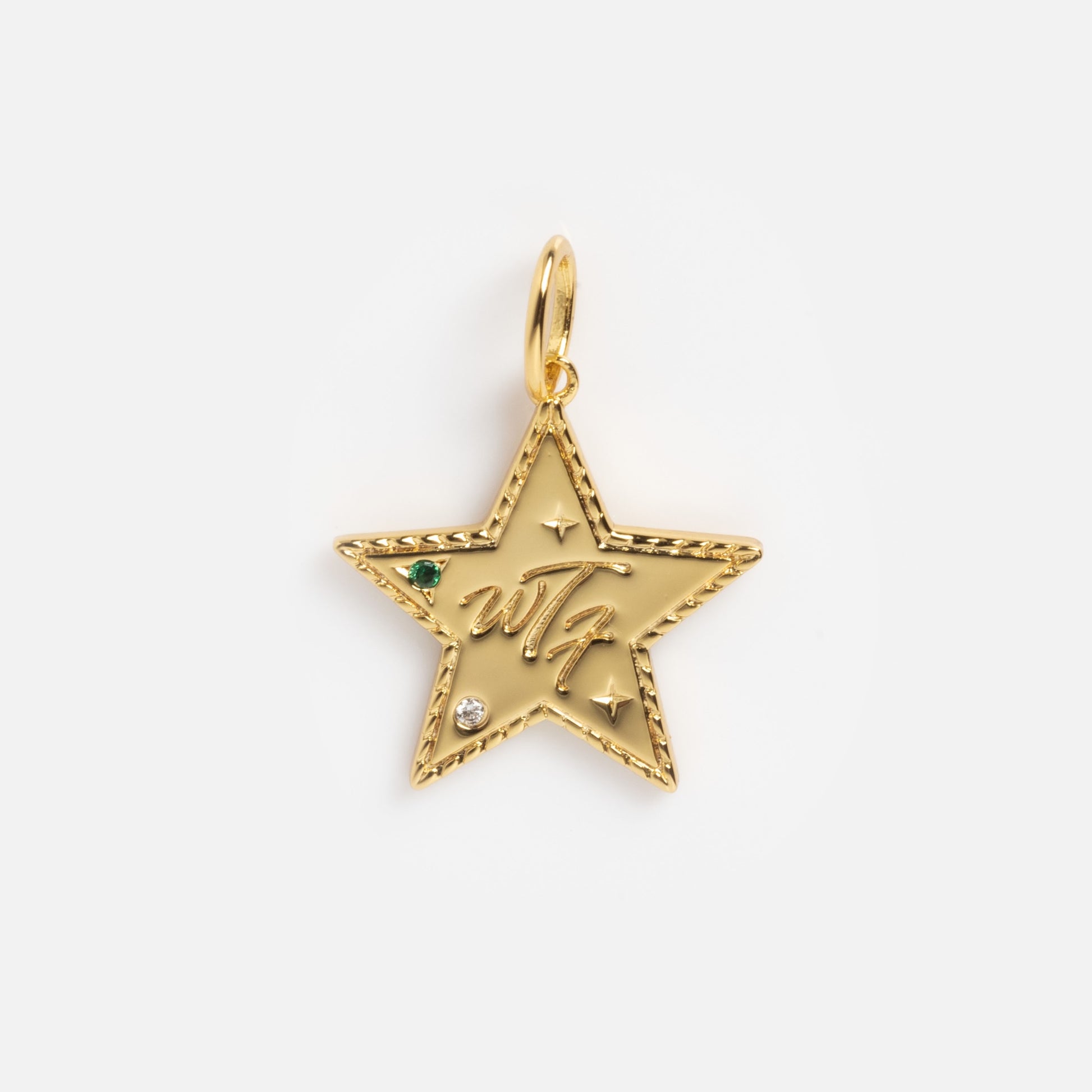 The Curse Word Charm is a gold star-shaped pendant featuring a textured edge, small green and clear gemstones, engraved stars, and the w7 initials in cursive on the front, attached to a gold loop.