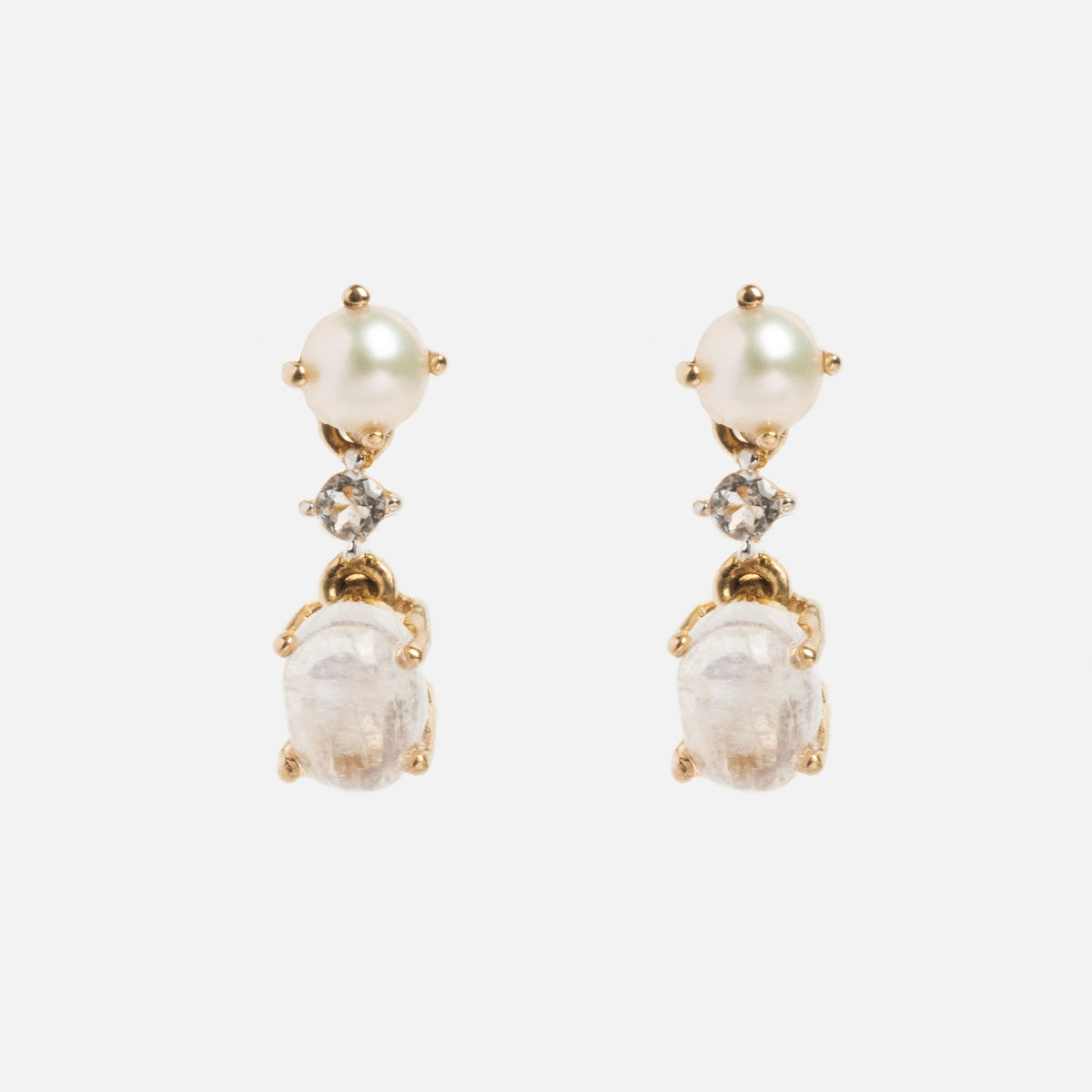 The Solid Gold Soft Glow Pearl and Moonstone Drop Studs feature a round pearl at the top, white topaz accents in the middle, and an oval-shaped moonstone dangling at the bottom.