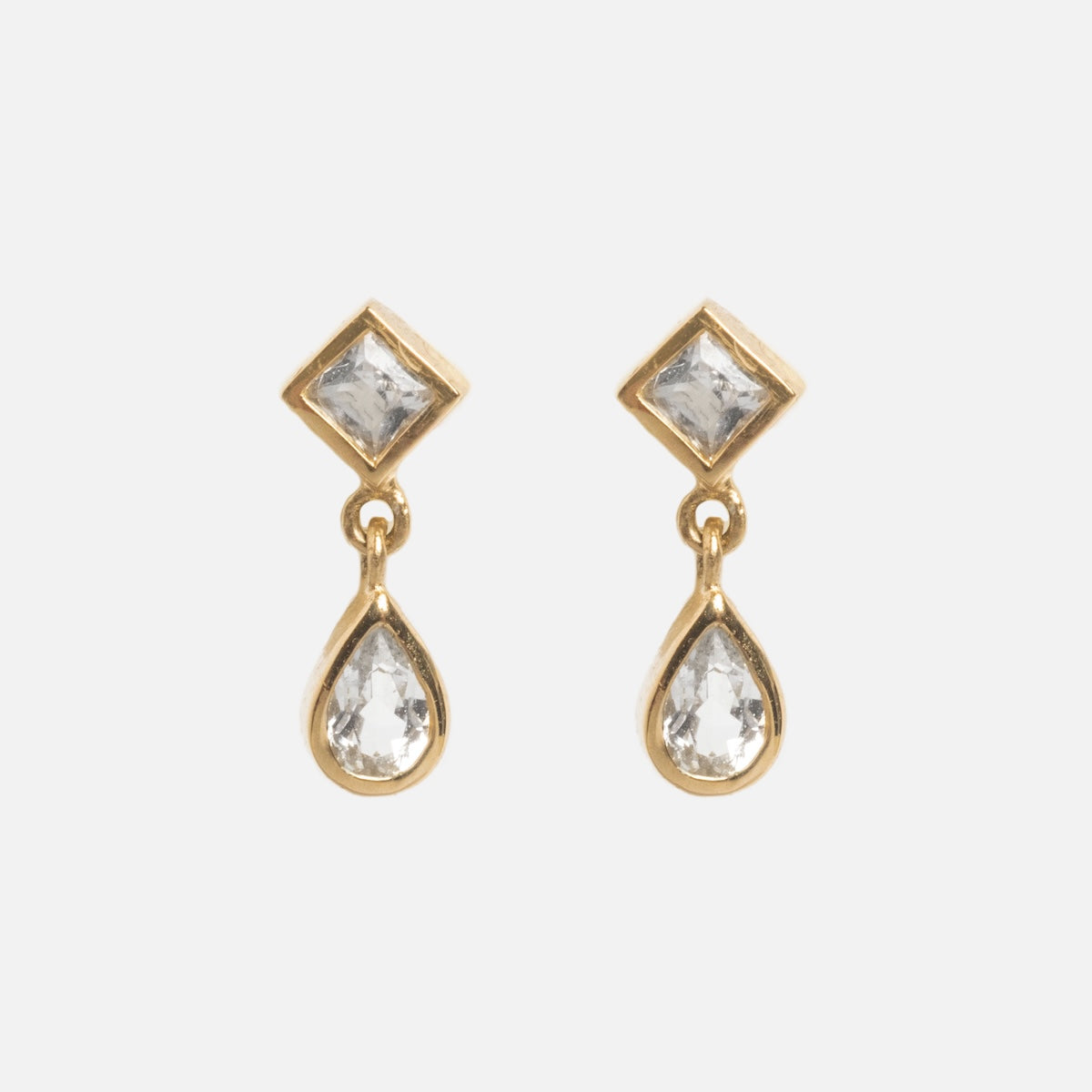 Solid Gold Radiant White Topaz Drop Studs feature square white topaz at the top and teardrop-shaped clear stones below, perfect for ear stacking. Shown on a plain white background.