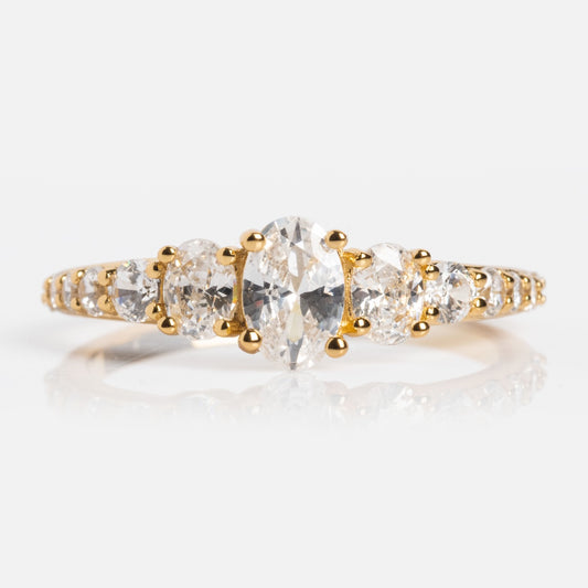 The True Colors Classic Ombre Birthstone Ring is a 14k gold plated ring with a central oval-cut diamond, accented by smaller oval and round diamonds, all set on a delicate gold band adorned with extra small diamonds.