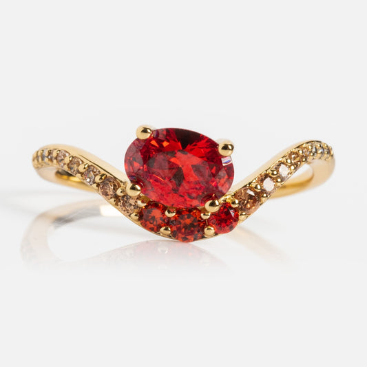 The Main Character Floating Ombre Birthstone Ring showcases an oval red gemstone center, two smaller red stones on each side, and a gold band gracefully curved and accented with sparkling diamonds.