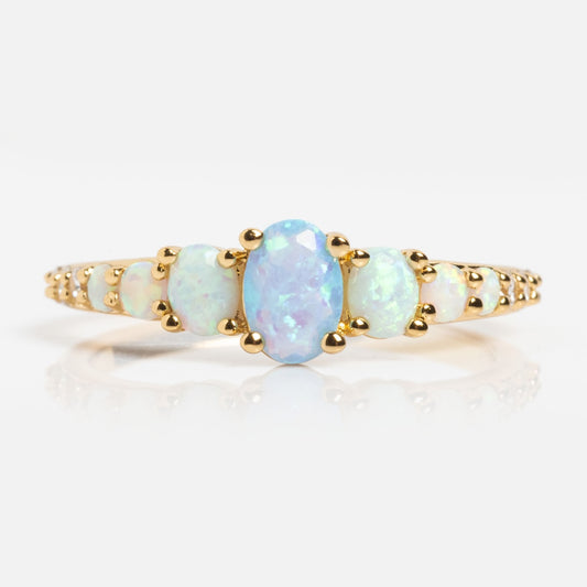 The True Colors Classic Ombre Birthstone Ring is a 14k gold plated ring with a row of prong-set oval opals, showcasing a larger central opal flanked by smaller stones, all displayed on a white background.