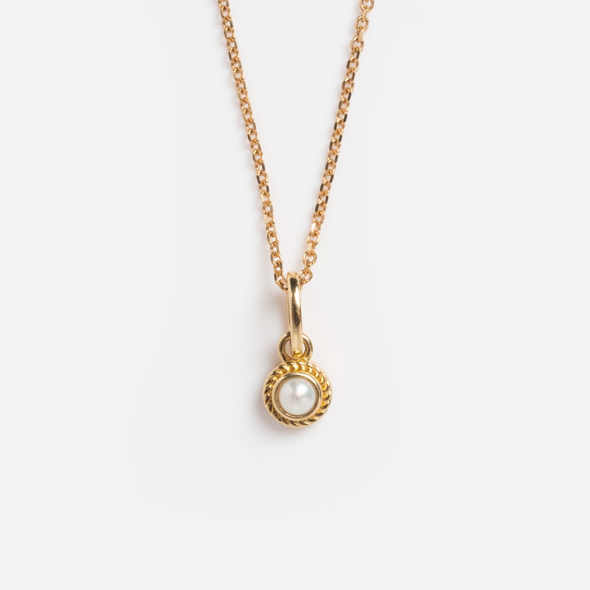 The Solid Gold Soft Glow Pearl Necklace is a vintage-inspired piece featuring a small round pendant with a white pearl set in a twisted gold bezel, displayed on a plain white background.