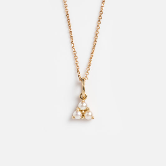 The Solid Gold Luminous Pearl Trio Necklace features a delicate gold chain with a triangular pendant of clustered white pearls, displayed on a plain white background.