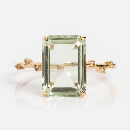 The Solid Gold Dewdrop Green Amethyst Statement Ring features a large rectangular green amethyst center and a delicate, textured band, shown against a plain white background.