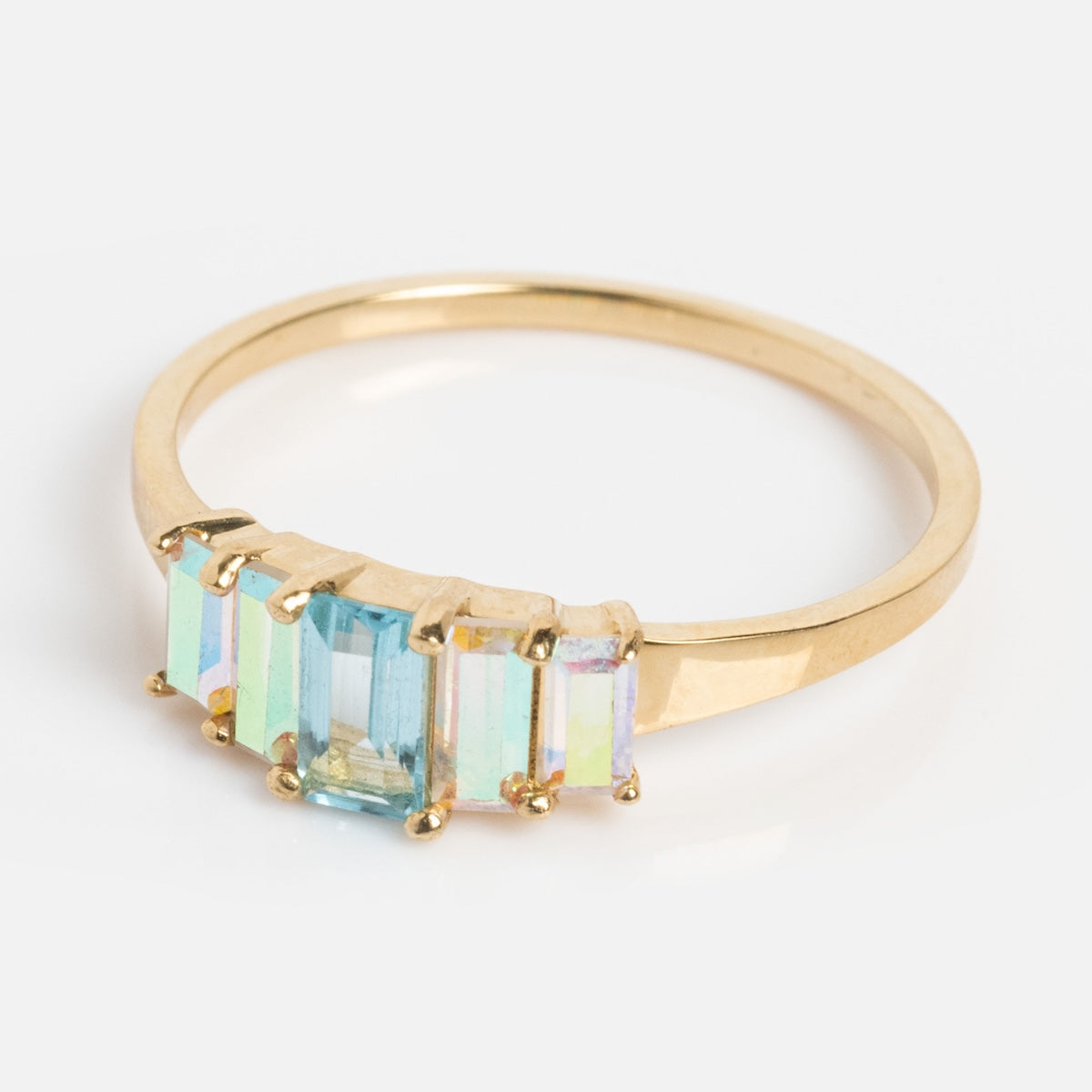 The Solid Gold Aurora Angel Aura Quartz and Blue Topaz Ring features five rectangular, iridescent stones set in a row, displayed on a plain white background.