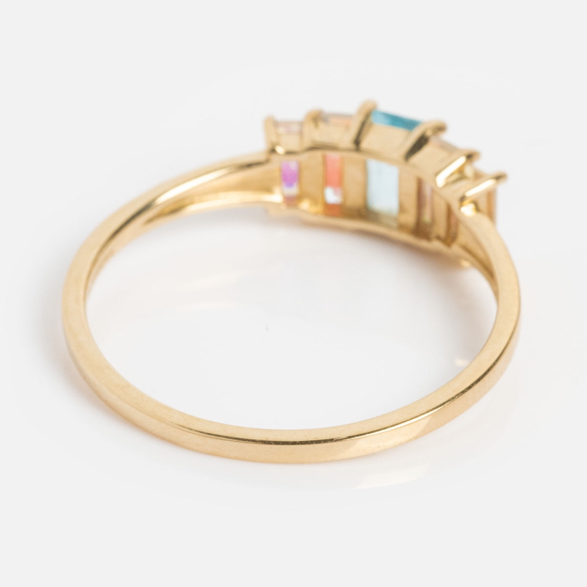 The Solid Gold Aurora Angel Aura Quartz and Blue Topaz Ring features five vibrant rectangular gemstones set side by side. An angled view highlights the backs of the stones and sleek band against a crisp white background.