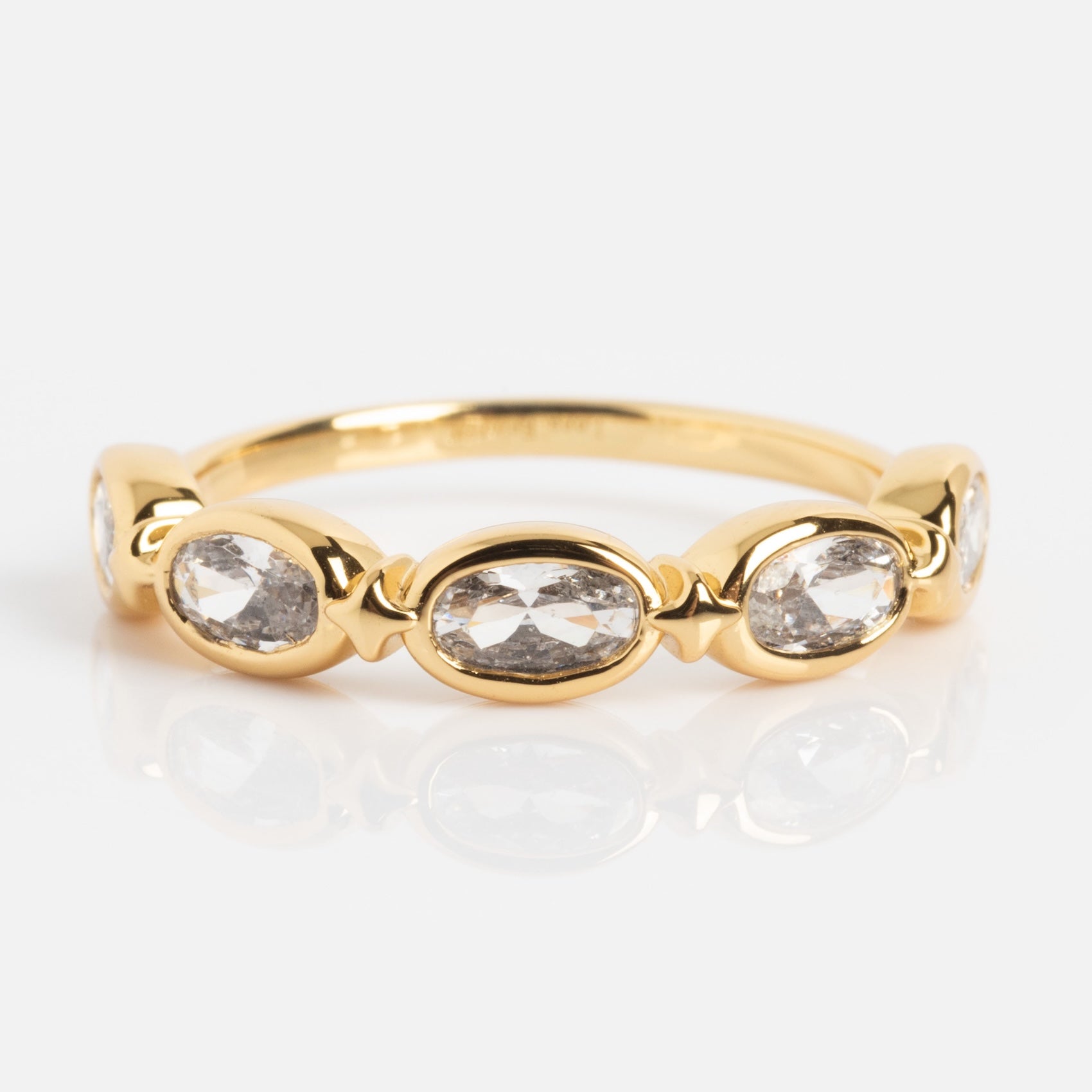 The Bold Moon Beam Stacking Ring showcases five oval clear gemstones in a row with gold accents, elegantly displayed on a white background.