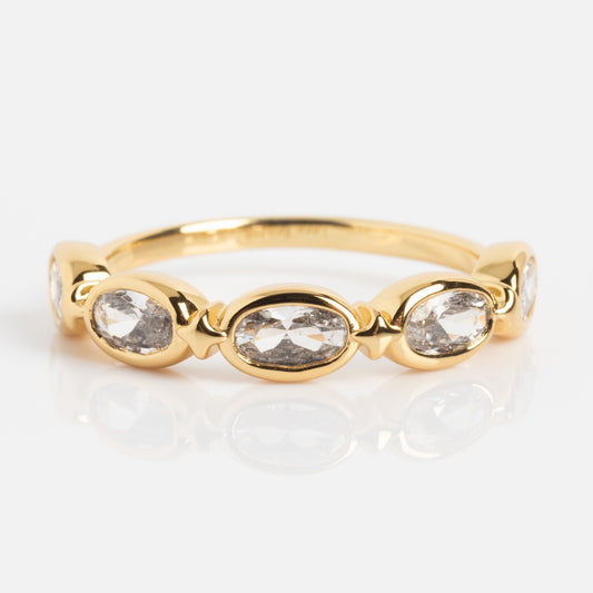 The Bold Moon Beam Stacking Ring showcases five oval clear gemstones in a row with gold accents, elegantly displayed on a white background.