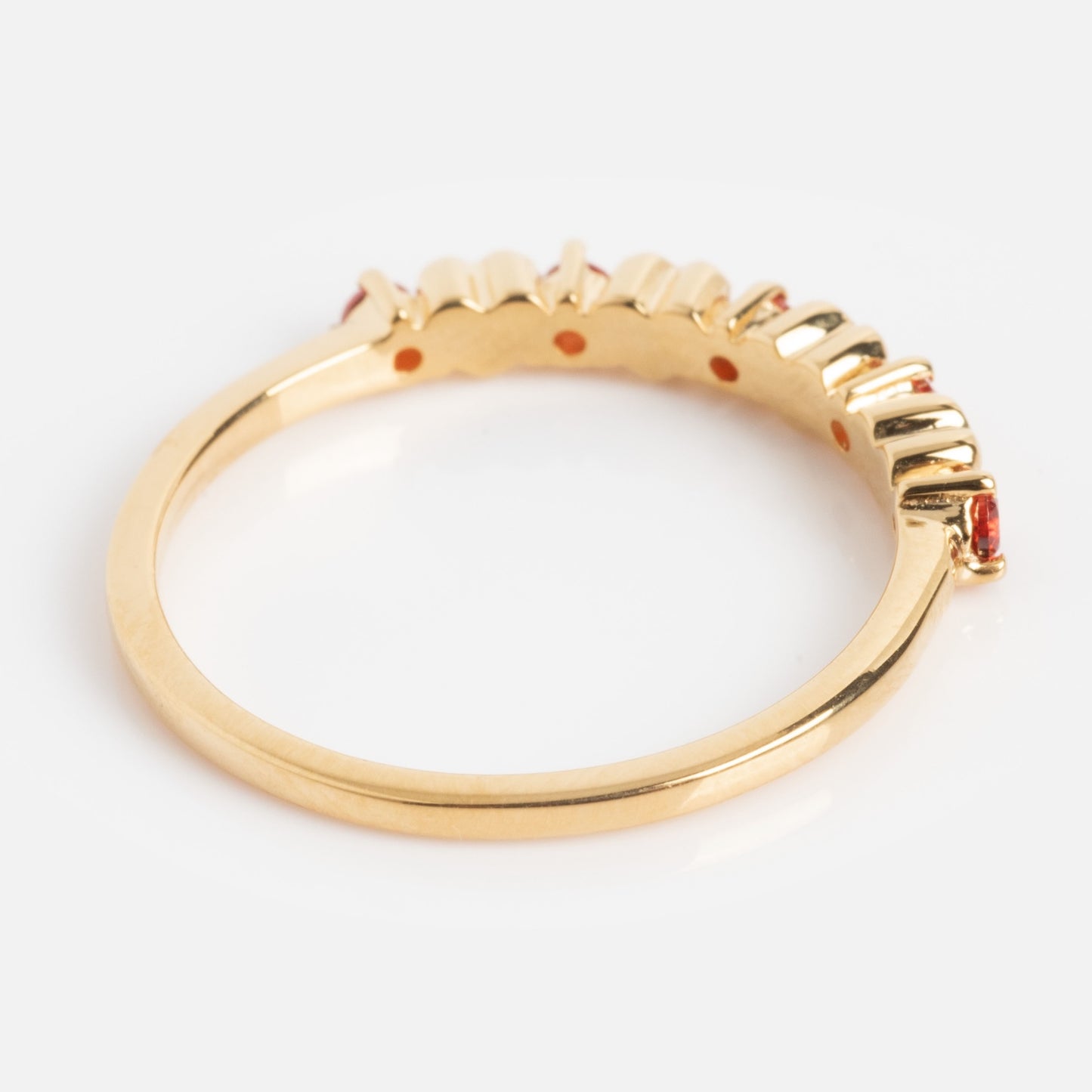 The Sweetheart Stacking Ring is a gold ring featuring a row of small red gemstones along the top, shown in a side view against a white background.