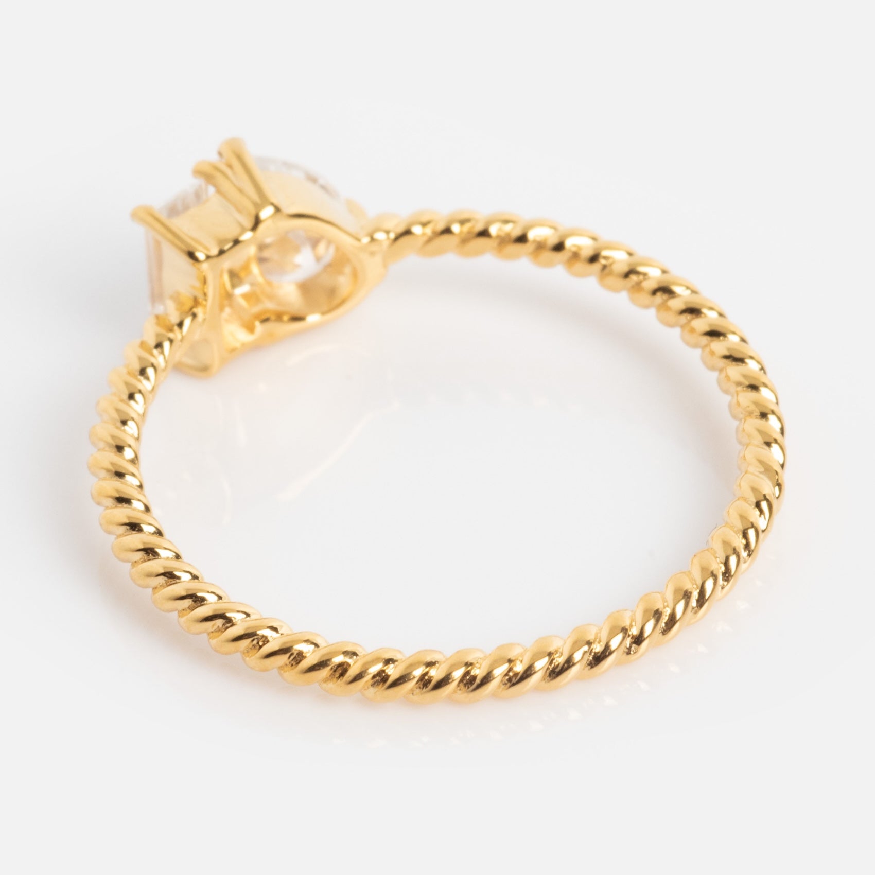 The Twisted Toi Et Moi Ring features a twisted rope-style gold band with a round, clear gemstone in a four-prong setting, shown on a white background.
