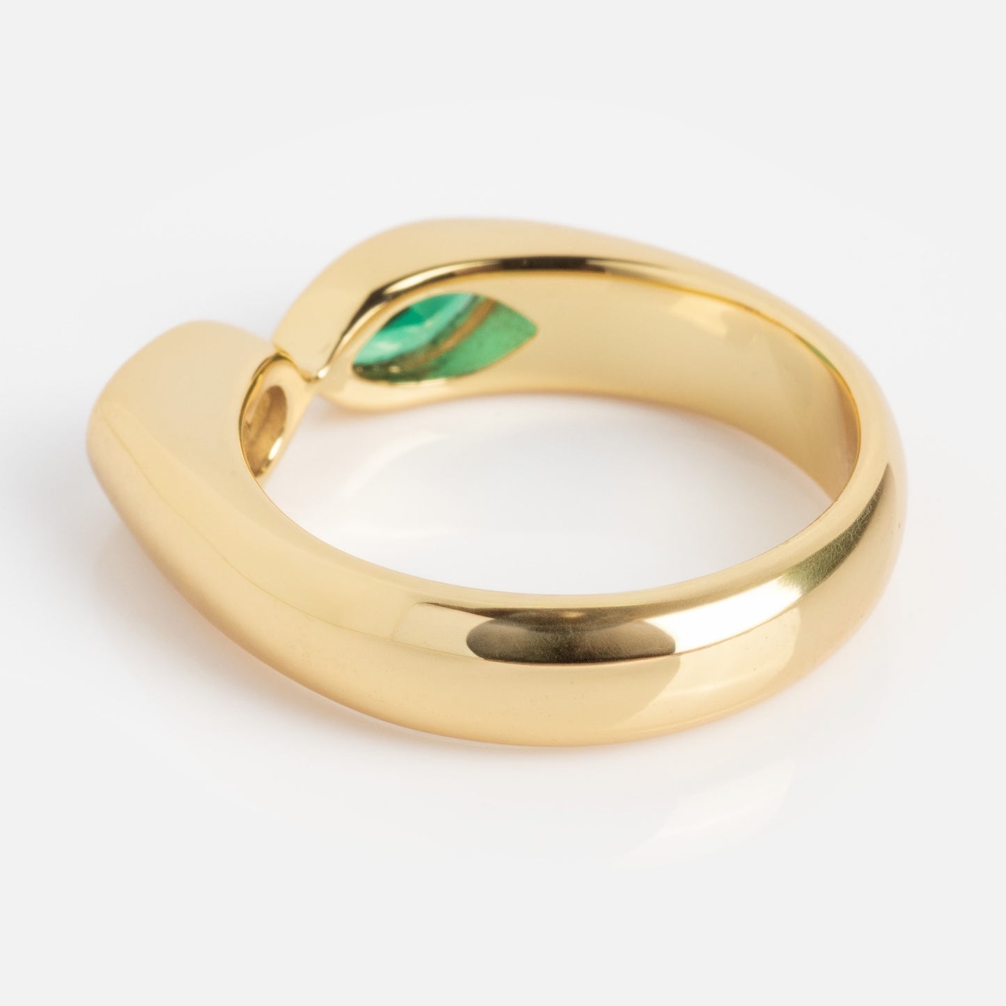 The Bold Toi Et Moi Pinky Ring features a modern, thick gold band that curves open at the top to reveal a small green gemstone set inside. Displayed on a white background.