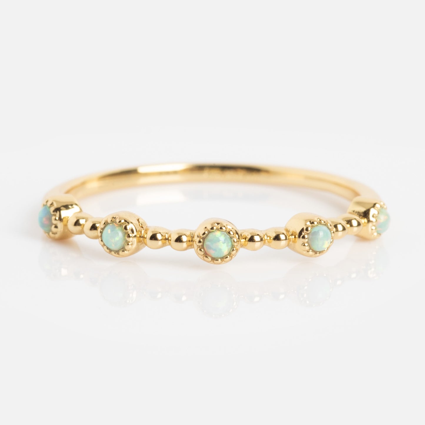 The Bezeled Beauty Stacking Ring showcases small, round opals set in decorative gold bezels evenly spaced around the band, accented with tiny gold beads for a delicate, elegant look.